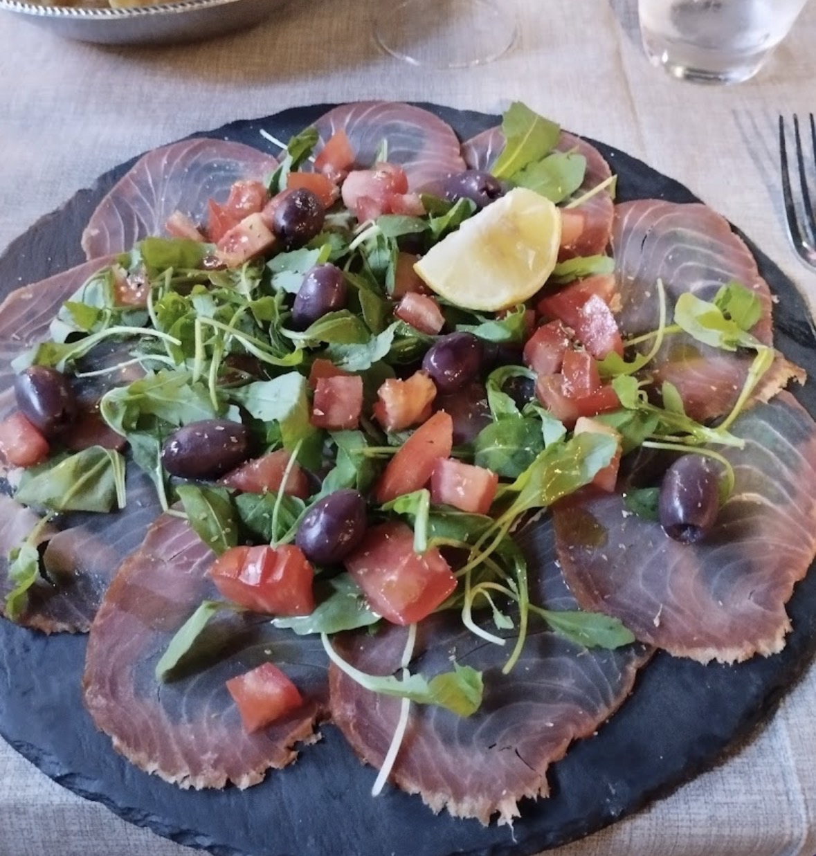 Carpaccio di tonno con rucola, pomodoro e olive
